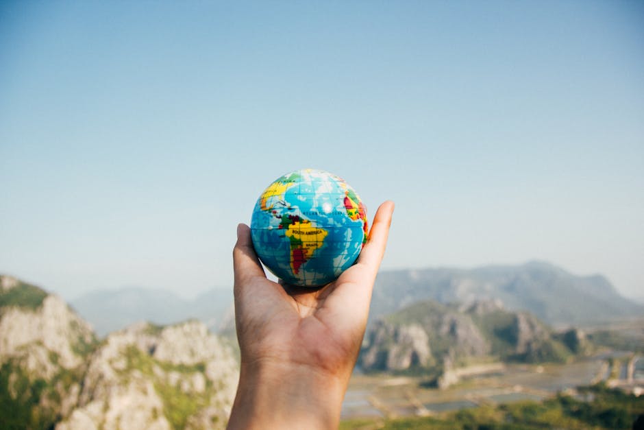 pexels-photo-346885-346885-1 Hand holding a globe against a mountain background symbolizing travel and exploration.